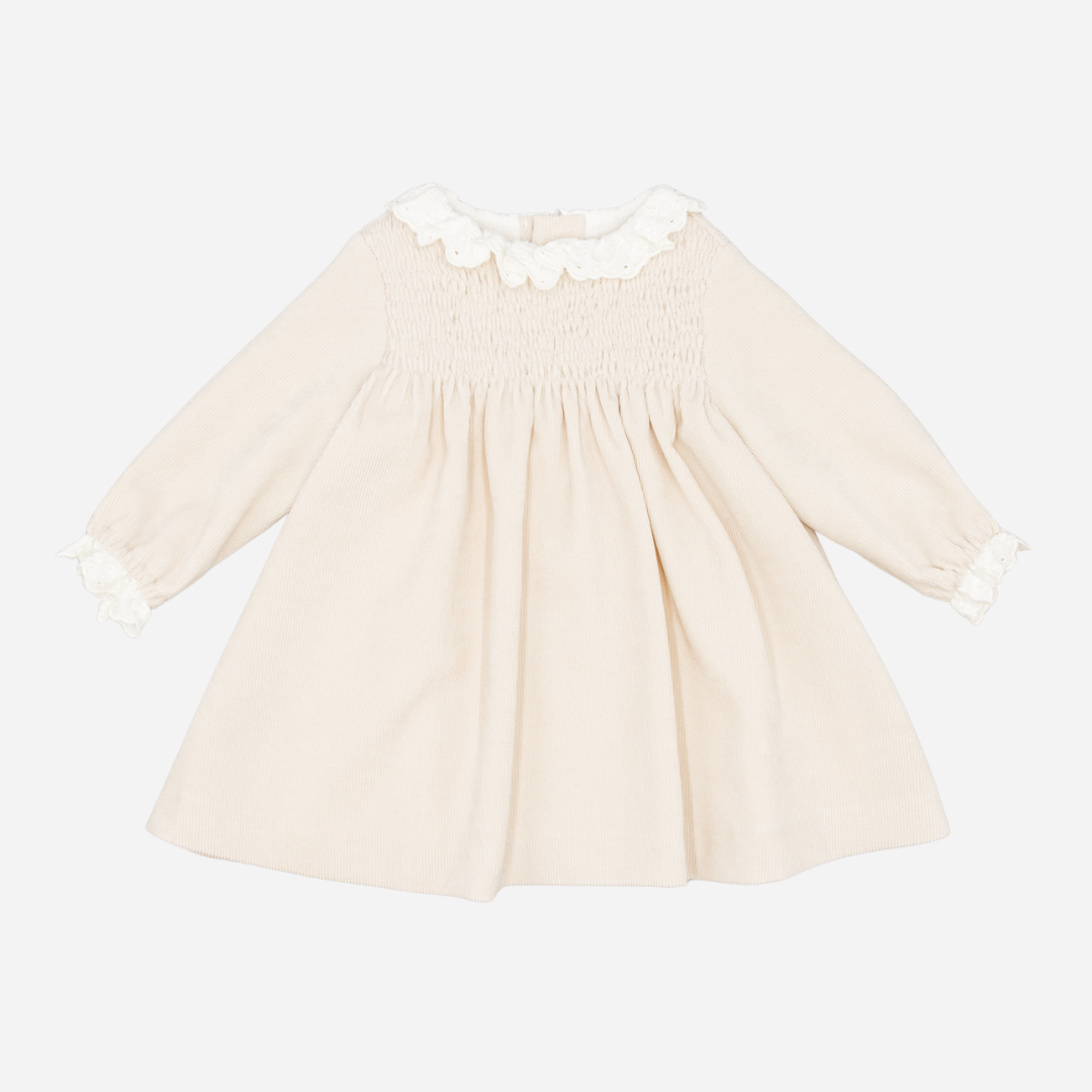Sold at Bombon shop, designed by Fina Ejerique, a beige corduroy baby dress with smocked bodice, white ruffle collar, and long sleeves. front