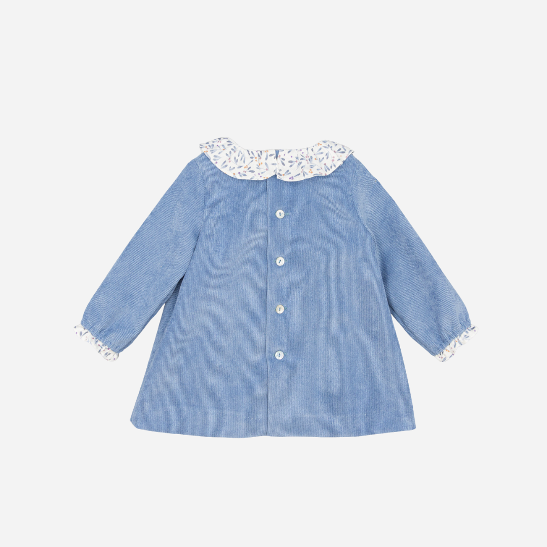 Sold at Bombon shop, designed by Fina Ejerique, a sky-blue corduroy baby dress with floral ruffle collar, bow detail, and long sleeves. back