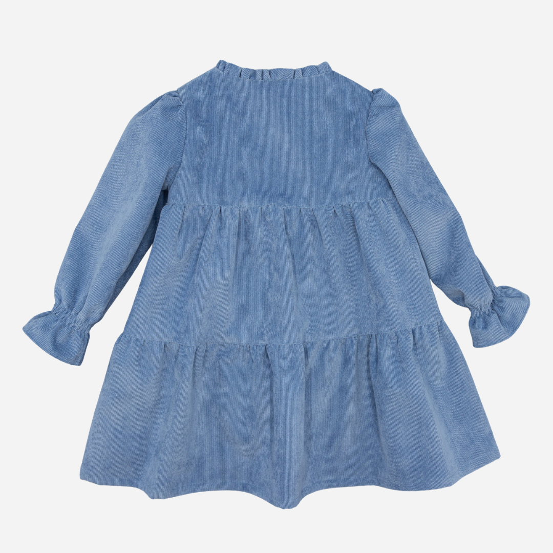Sold at Bombon shop, designed by Fina Ejerique, a blue corduroy baby dress with ruffle trim, button front, and long sleeves. back