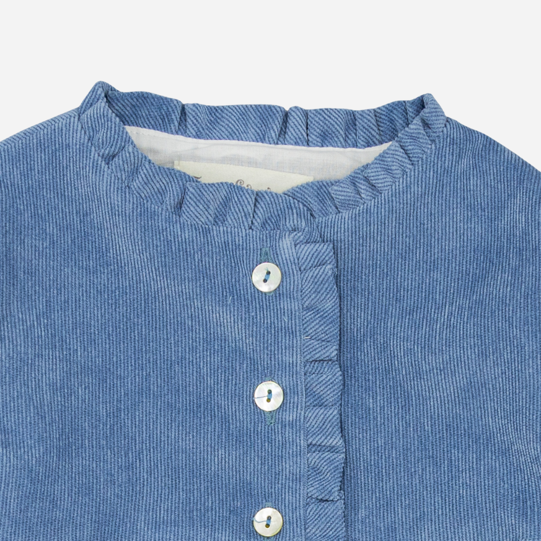 Sold at Bombon shop, designed by Fina Ejerique, a blue corduroy baby dress with ruffle trim, button front, and long sleeves. zoom