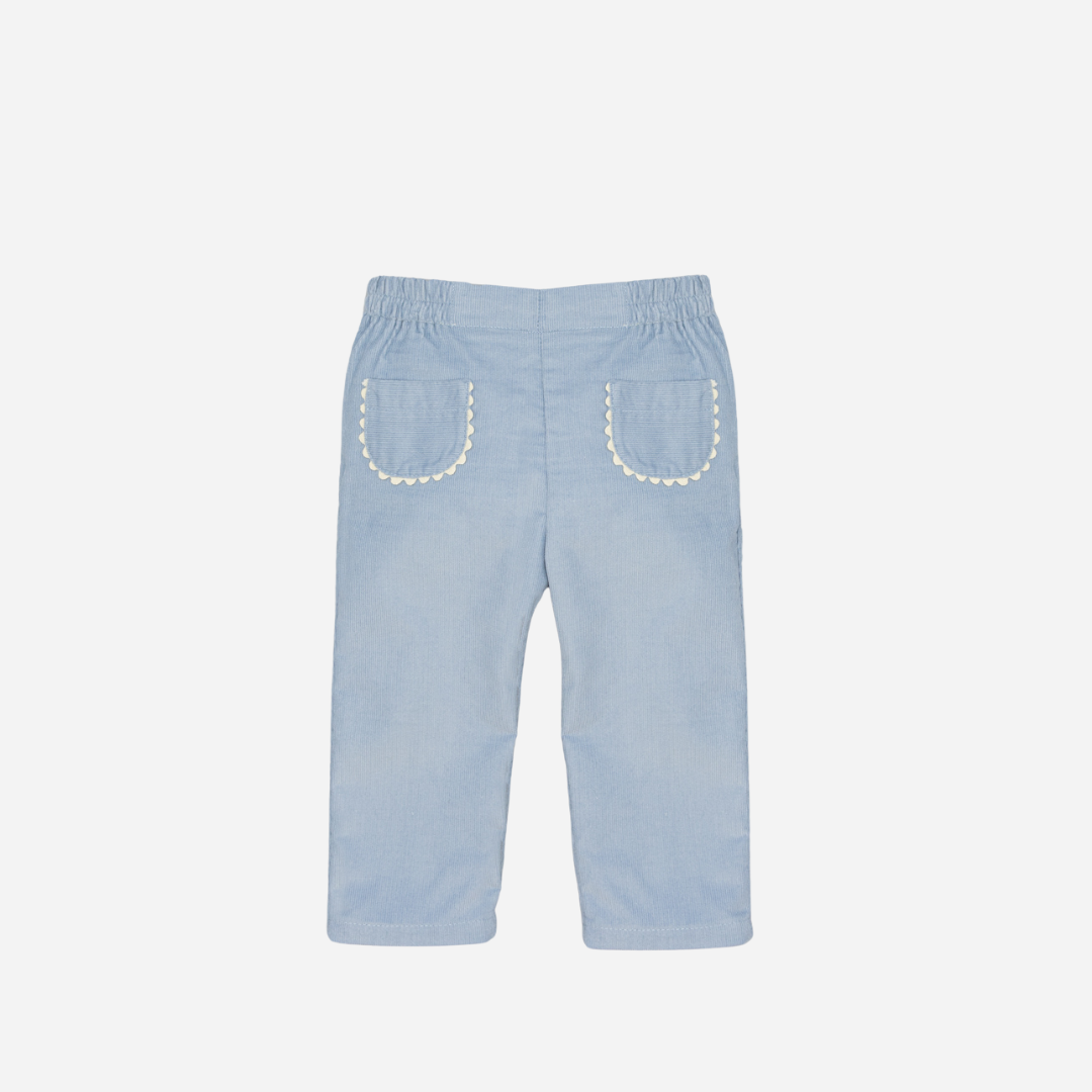 Sold at Bombon shop, designed by Fina Ejerique, a pair of sky-blue corduroy baby pants with scallop-trimmed back pockets and elastic waistband. front