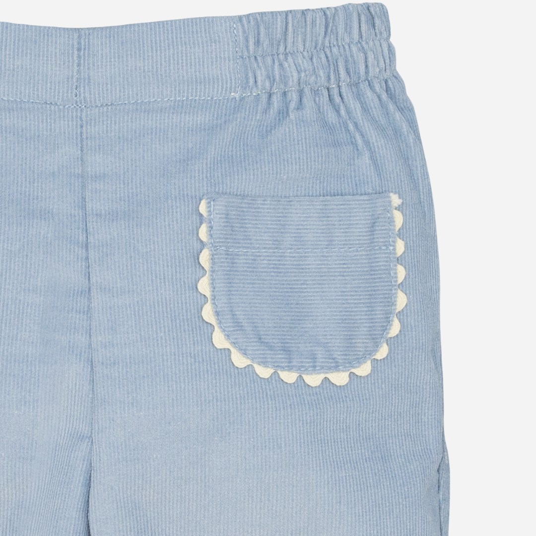 Sold at Bombon shop, designed by Fina Ejerique, a pair of sky-blue corduroy baby pants with scallop-trimmed back pockets and elastic waistband. zoom