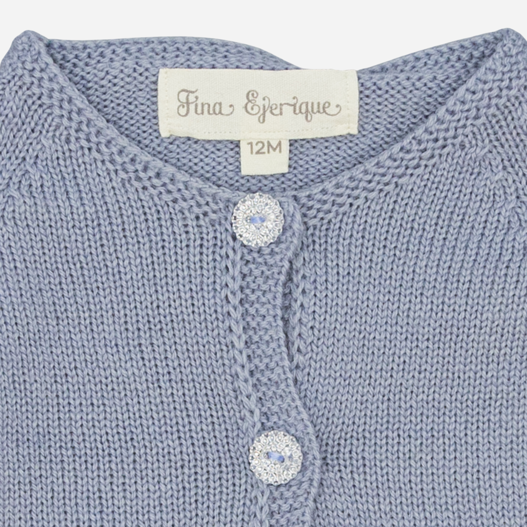 Sold at Bombon shop, designed by Fina Ejerique, a powder-blue knit baby cardigan with scalloped trim and front buttons. zoom