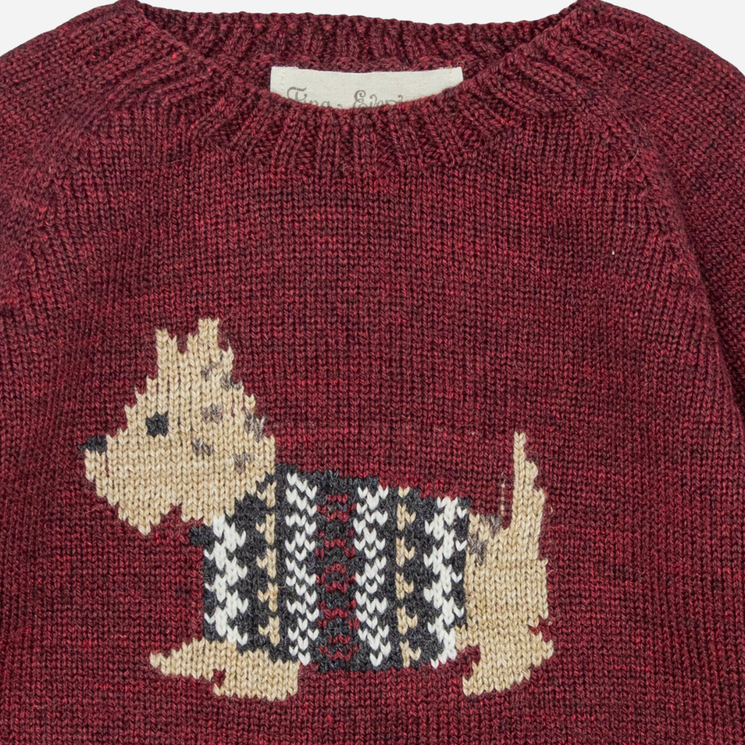 Sold at Bombon shop, designed by Fina Ejerique, a burgundy knit baby sweater with a dog motif in a houndstooth sweater. zoom