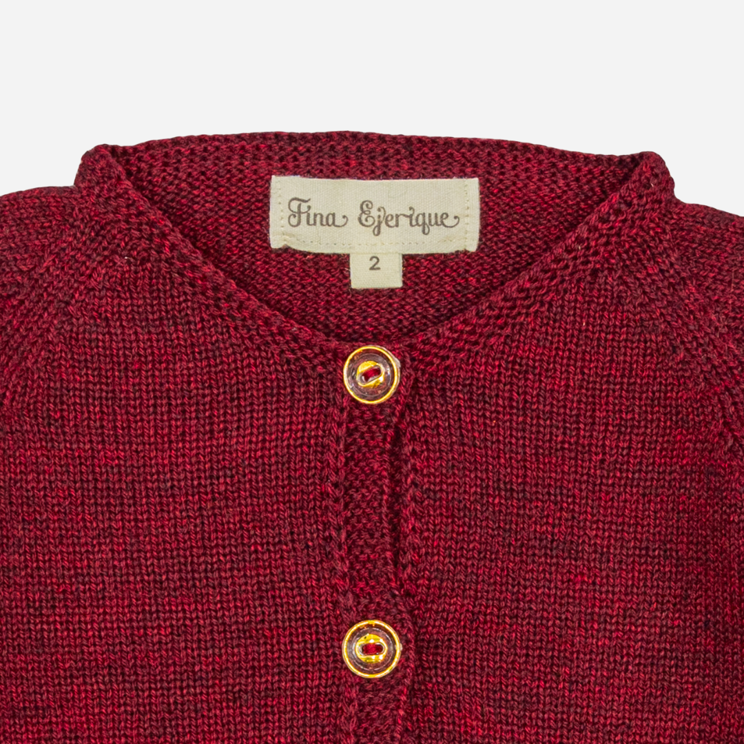 Sold at Bombon shop, designed by Fina Ejerique, a burgundy knit baby cardigan with wooden buttons and scalloped trim. zoom