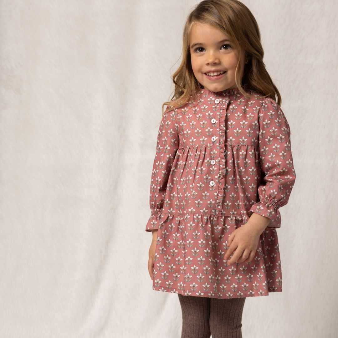 Young girl wearing a pink floral dress against a plain background