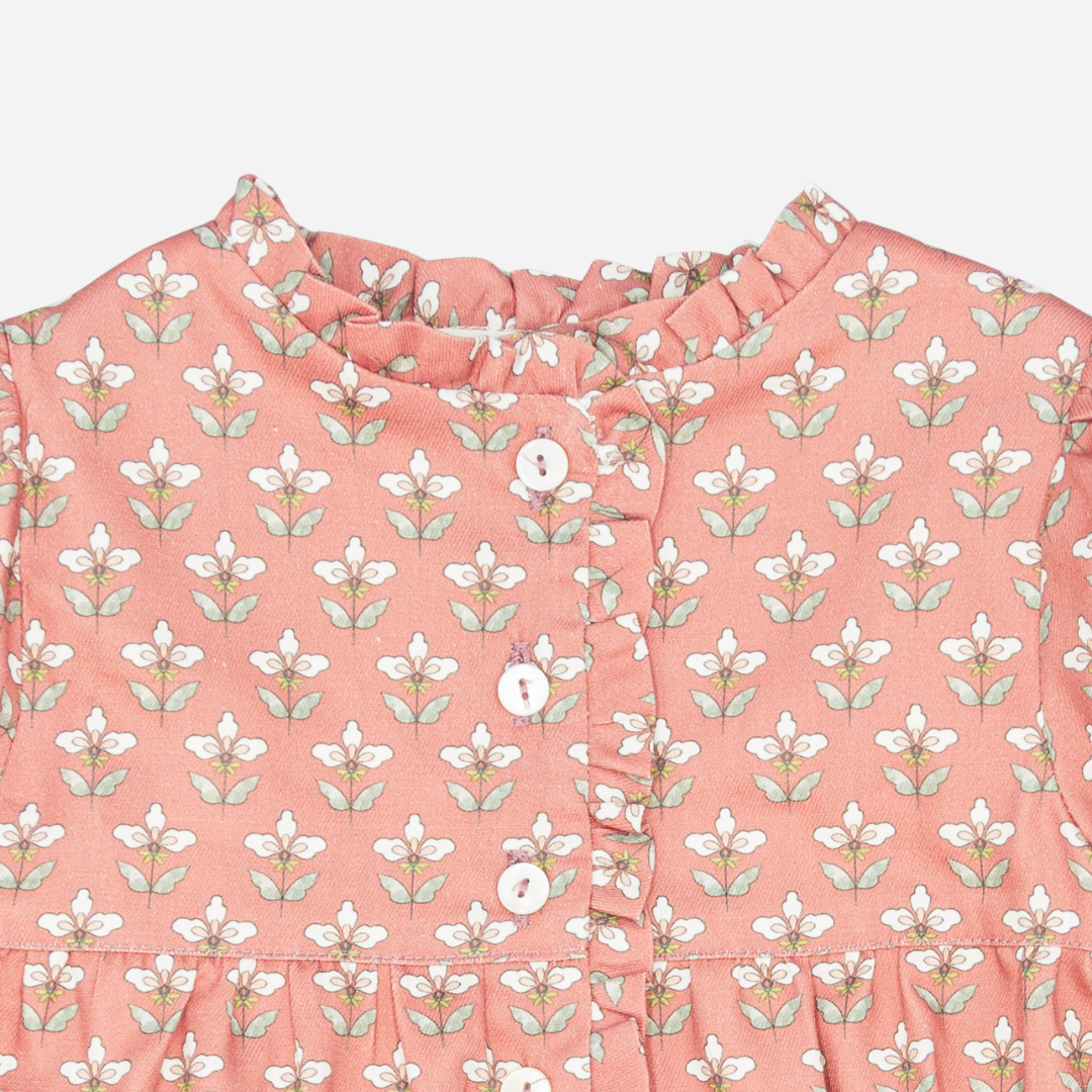 Pink blouse with white floral pattern on a light pink background
