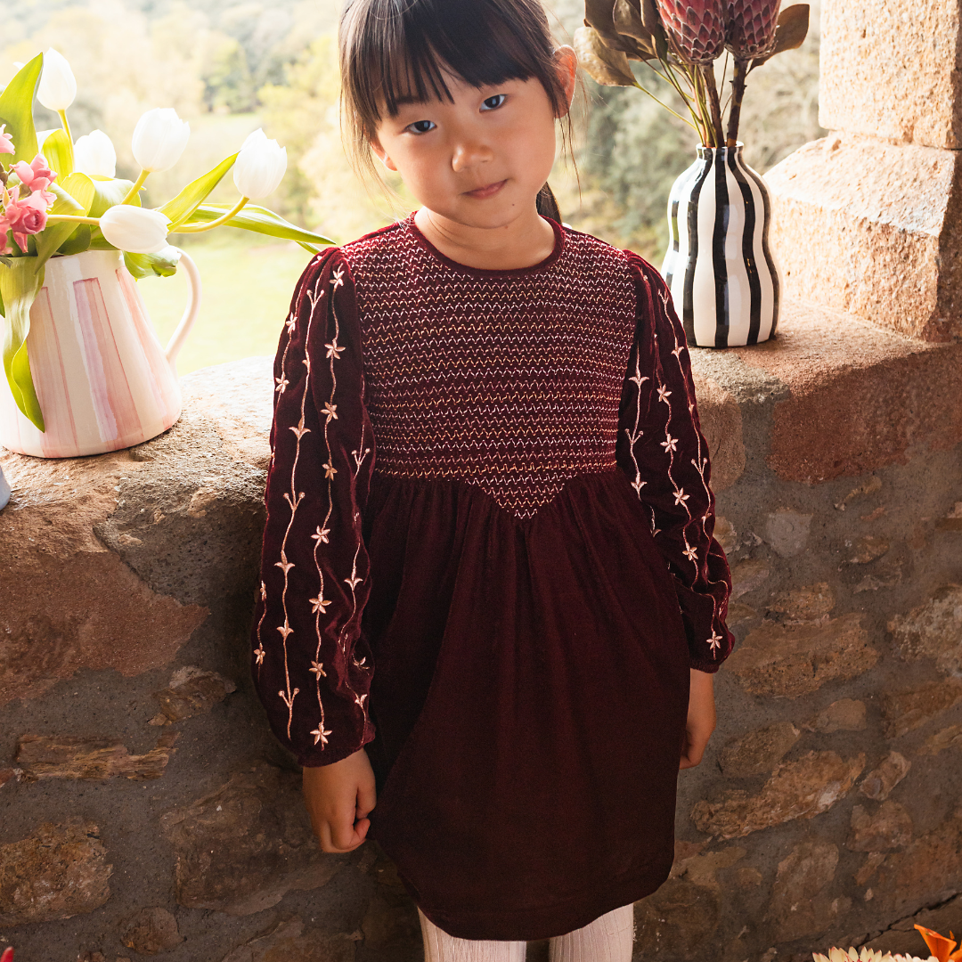 sold at Bombon shop, designed by Bachaa Paris, Dress, Velvet in Burgundy color, Plain lining in organic cotton voile, Fully hand embroidered sleeves with a golden thread, Smocked front, Gathered at the front and back, Golden buttons at the back. model view