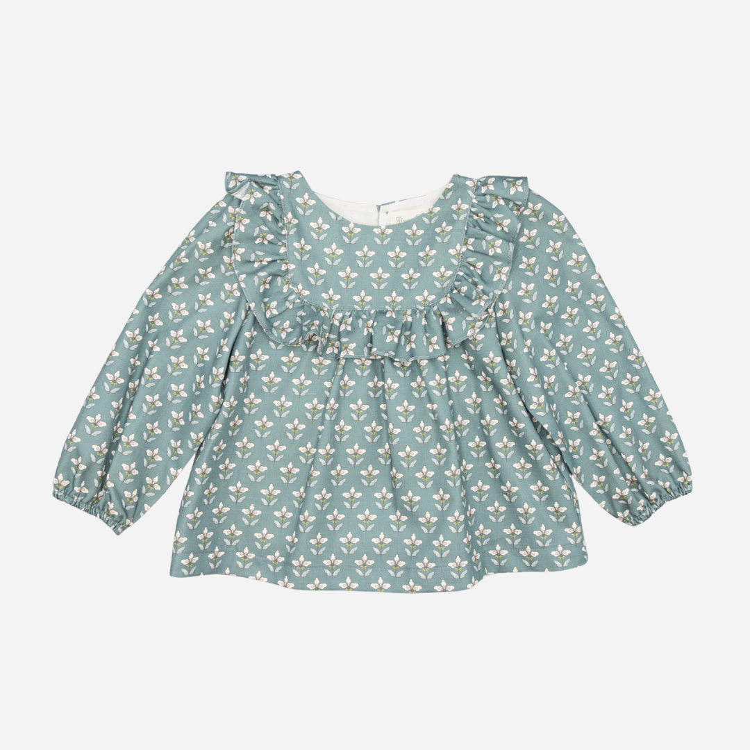 Sold at Bombon shop, designed by Fina Ejerique, a green floral viyella baby blouse with ruffled yoke and long sleeves, styled to pair with green corduroy shorts. front