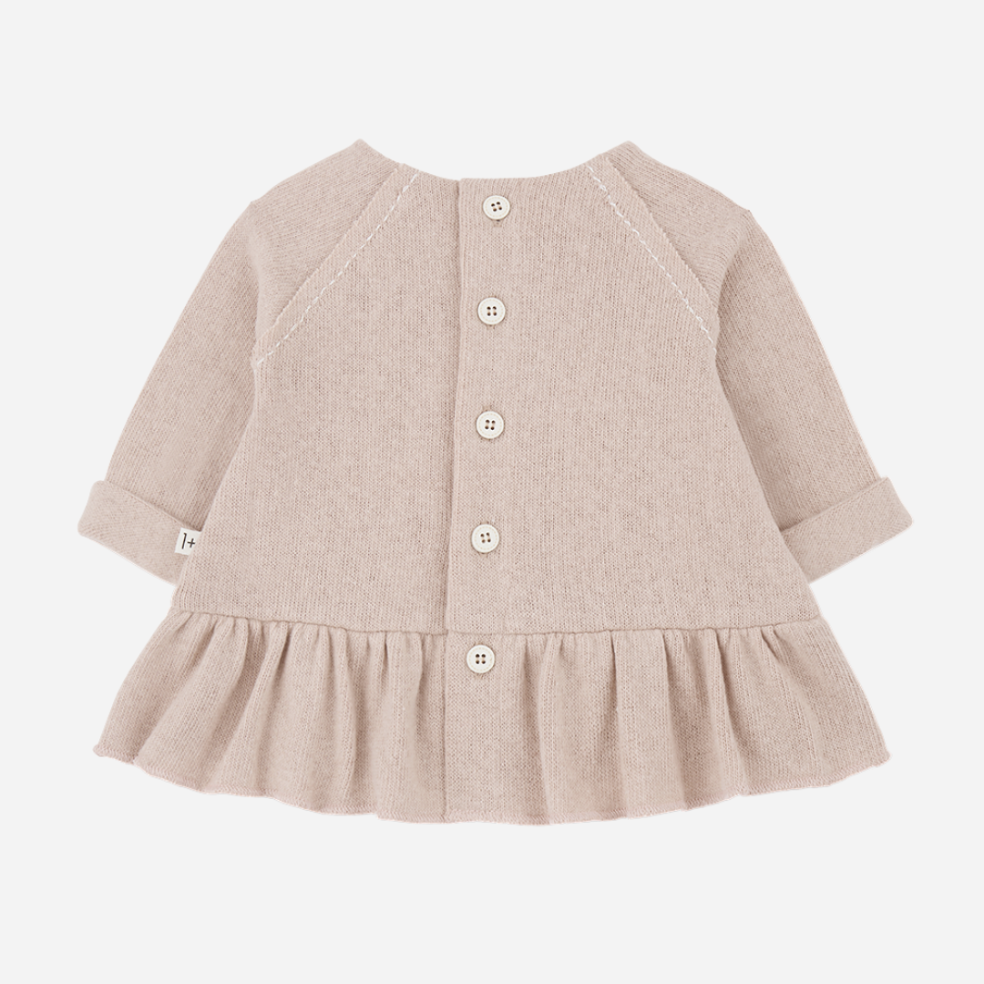 Sold at Bombon shop, designed by 1+ in the family — nude long-sleeve baby dress with ruffled hem and front patch pocket. back