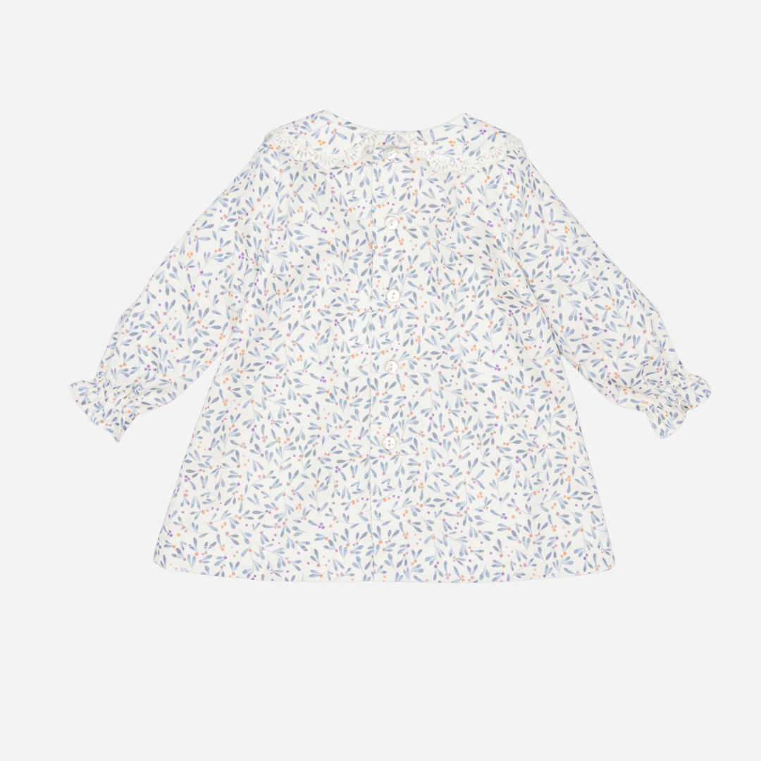 Sold at Bombon shop, designed by Fina Ejerique, a white baby dress with blue, lilac, and peach leaf print, lace-trim collar, blue buttons, and long sleeves. back