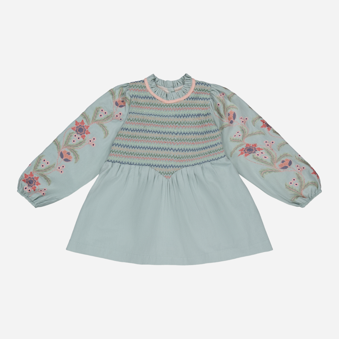 sold at Bombon shop, designed by Bachaa, Blouse/Short dress, Blue color, Organic cotton twill (167 g/m²), Plain lining in organic cotton voile, Long embroidered and elasticated sleeves, Smocked chest, Ruffled collar, Tone-on-tone buttons and belt at the back. front view