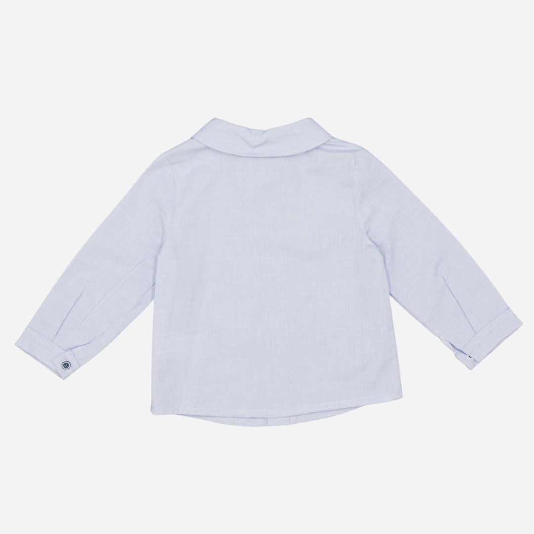 Sold at Bombon shop, designed by Fina Ejerique, a light-blue cotton baby shirt with rounded collar, long sleeves, and matching buttons back