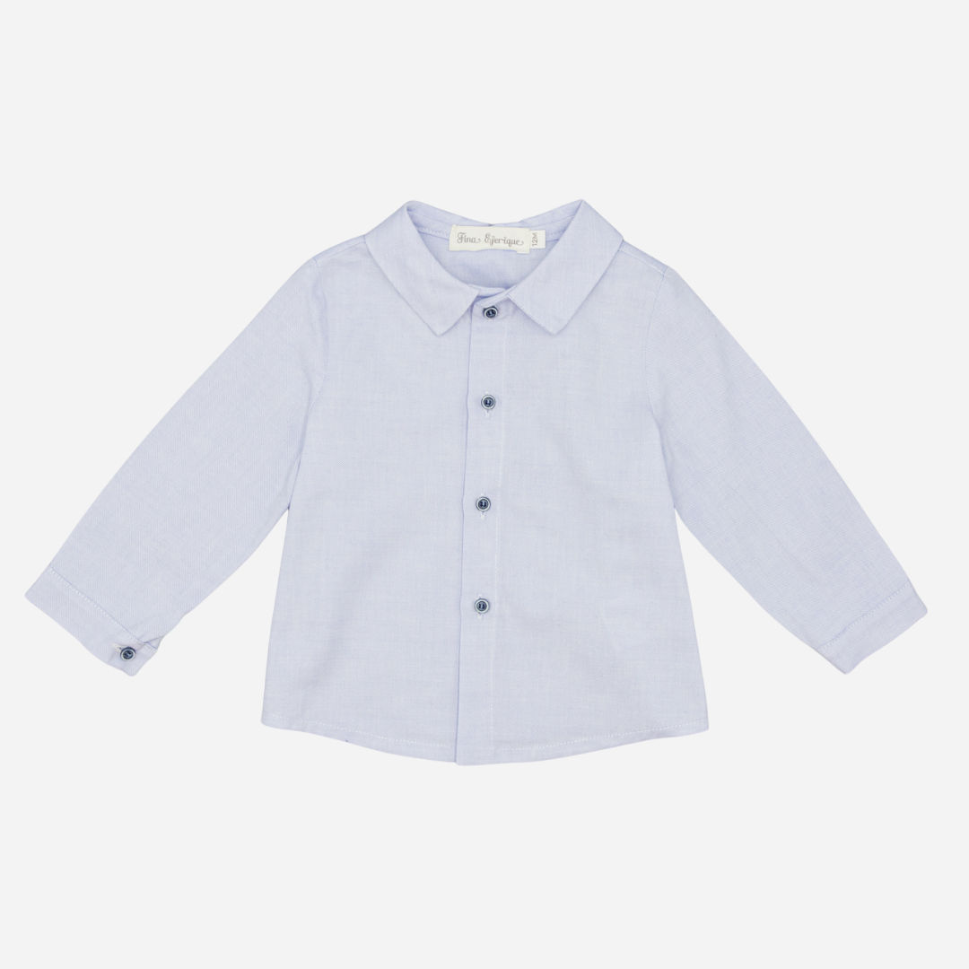 Sold at Bombon shop, designed by Fina Ejerique, a light-blue cotton baby shirt with rounded collar, long sleeves, and matching buttons. front