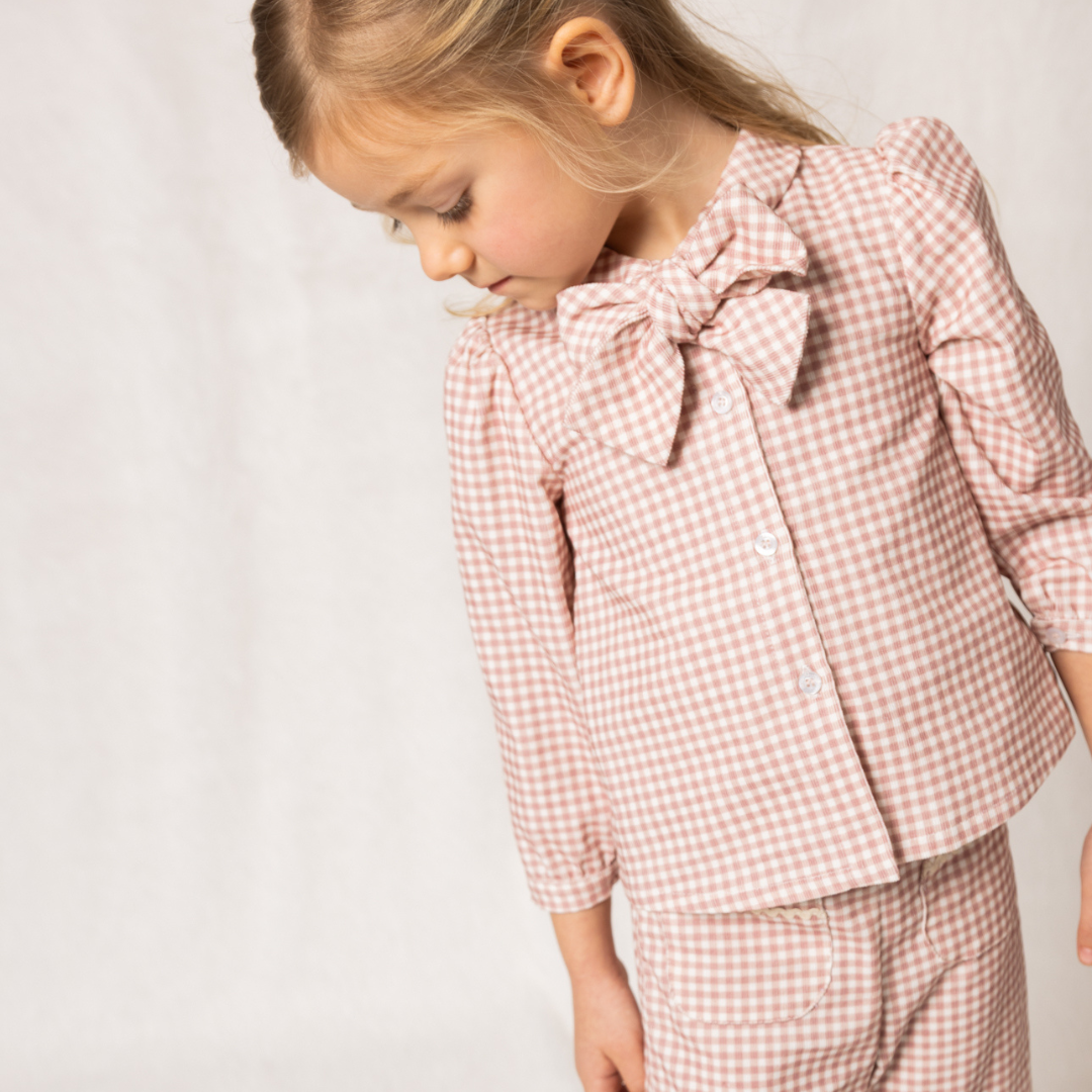 Sold at Bombon shop, designed by Fina Ejerique, pink gingham corduroy baby pants with ric-rac trim on the back pockets, styled to pair with the matching blouse. model