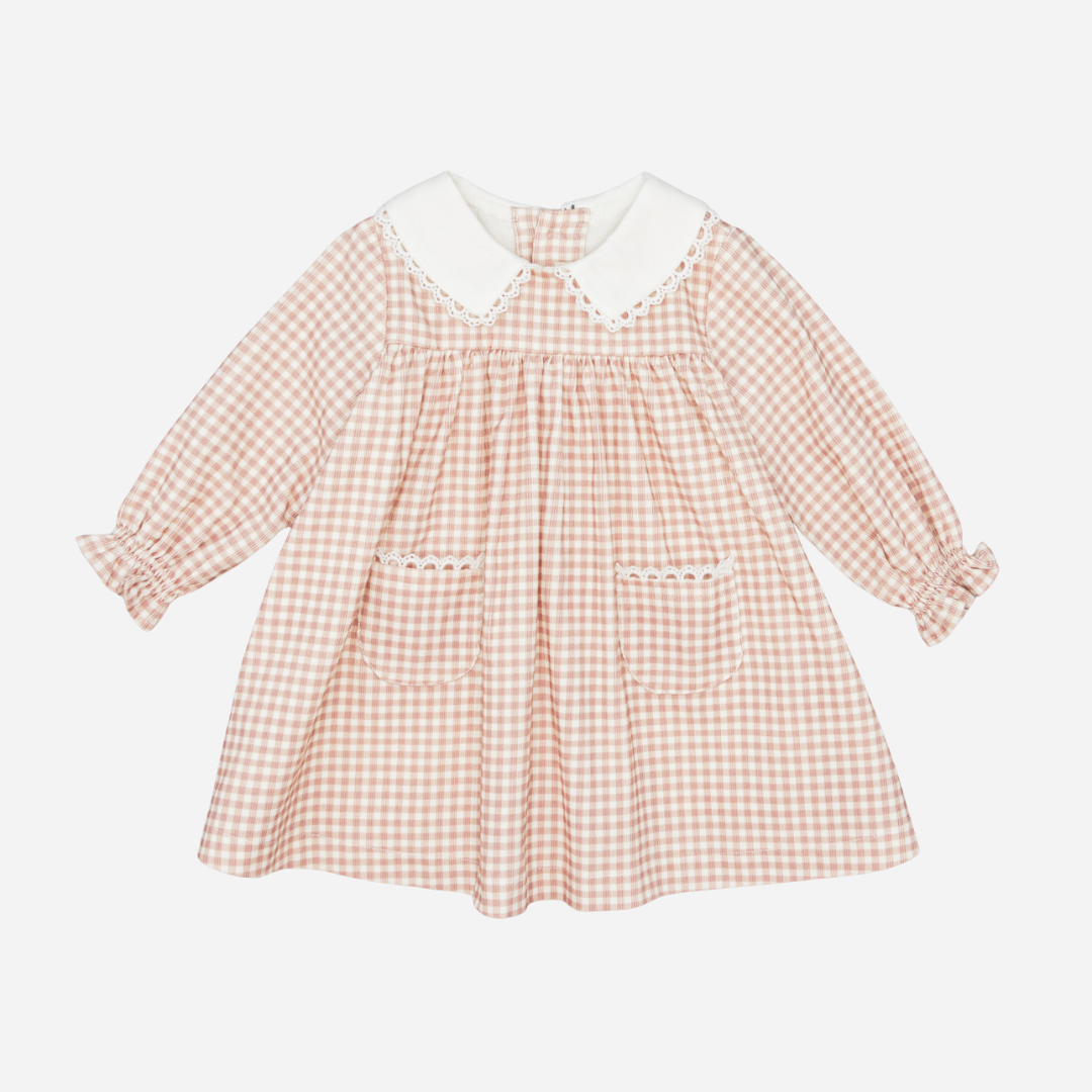 Sold at Bombon shop, designed by Fina Ejerique, a blush-pink gingham baby dress with white collar, lace trim, front pockets, and long sleeves. front