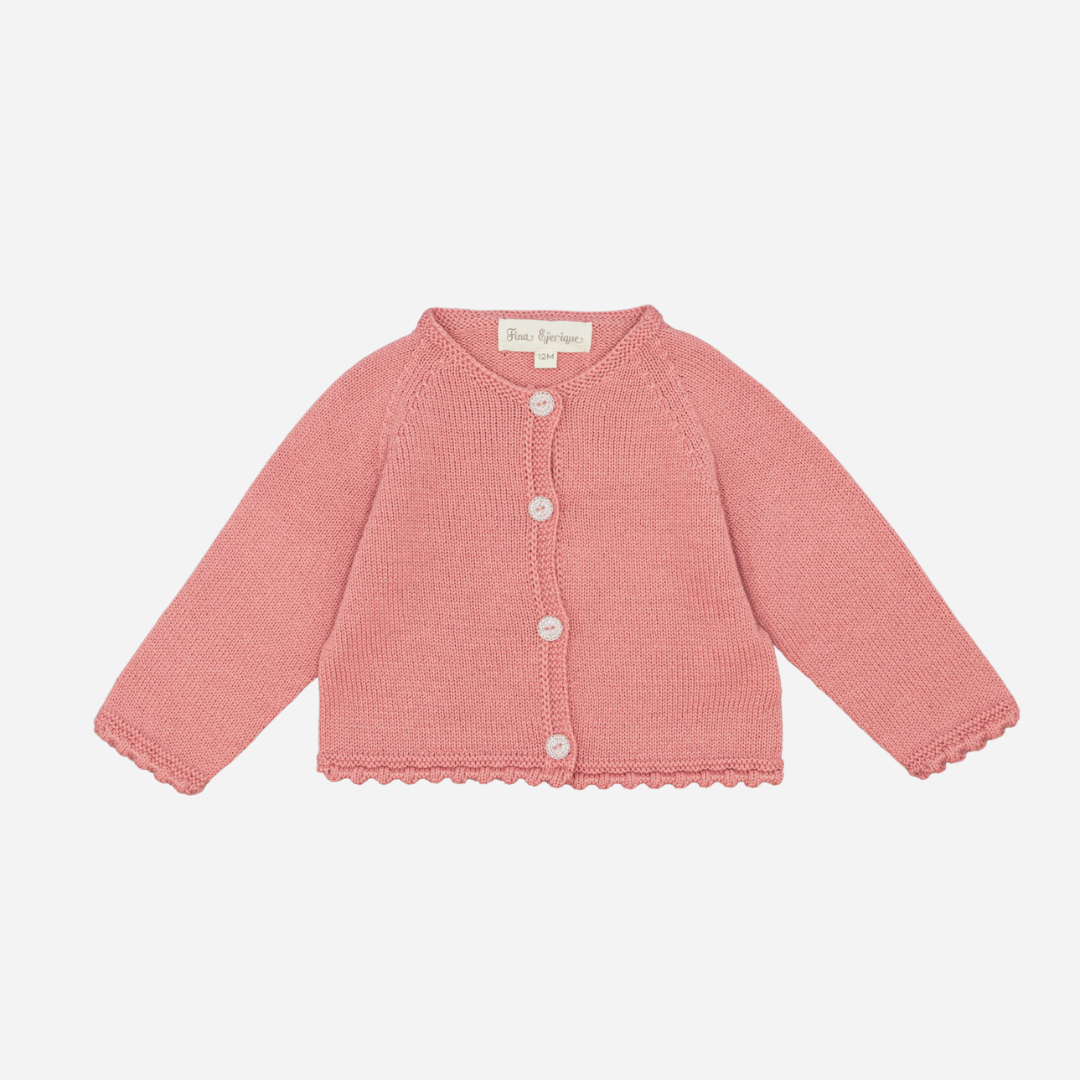 Sold at Bombon shop, designed by Fina Ejerique, a rose-pink knit baby cardigan with scalloped trim and front buttons. front