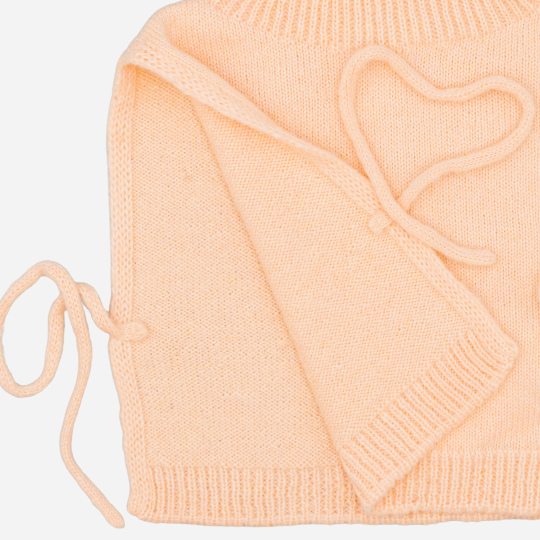 Sold at Bombon shop, designed by Fina Ejerique, pink knit vest with turtleneck and side ties, pairs perfectly with the floral blouse and beige textured skirt. side