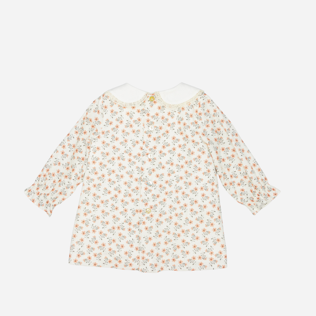 Sold at Bombon shop, designed by Fina Ejerique, a white viyella baby dress with pink and green floral print, Peter Pan collar with lace trim, pleated front, and long sleeves. back