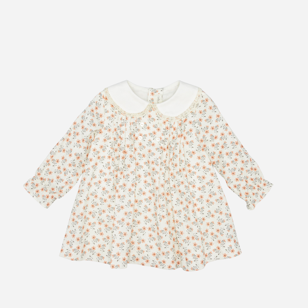 Sold at Bombon shop, designed by Fina Ejerique, a white viyella baby dress with pink and green floral print, Peter Pan collar with lace trim, pleated front, and long sleeves. front