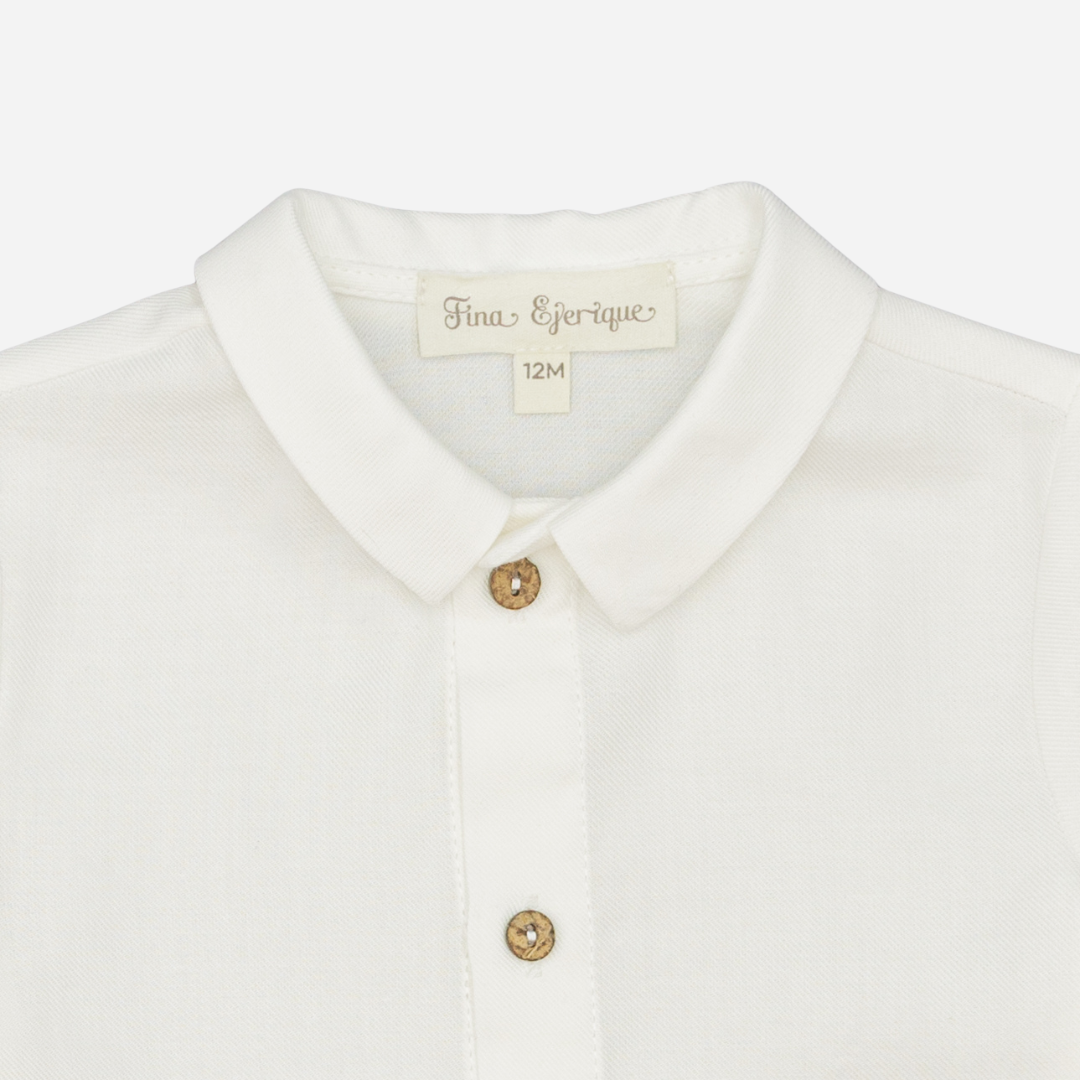 Sold at Bombon shop, designed by Fina Ejerique, a white viyella baby shirt with rounded collar, wooden buttons, and long sleeves. zoom
