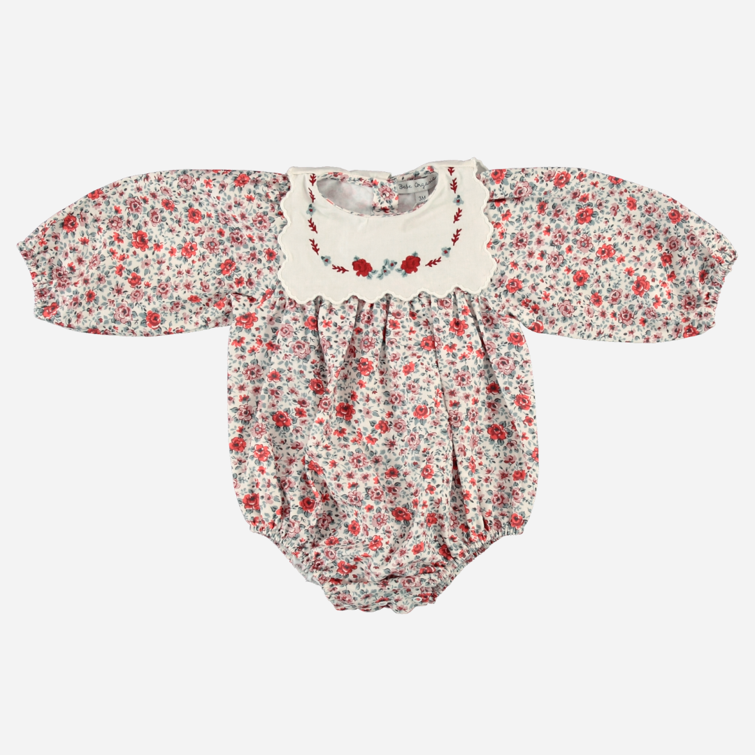 Sold at Bombon Shop, this baby girl romper by Bebe Organic features a vintage floral print in red and dusty blue, puffed long sleeves, and a cream scalloped collar with delicate embroidery — a charming one-piece perfect for fall layering or special moments.