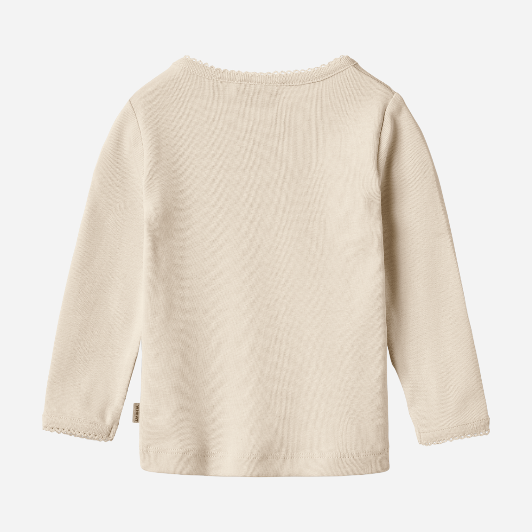 Sold at Bombon shop, designed by Wheat, this eggshell-colored ribbed long-sleeve tee features picot edging and a snap closure at the shoulder. back