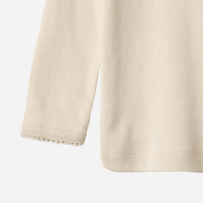 Sold at Bombon shop, designed by Wheat, this eggshell-colored ribbed long-sleeve tee features picot edging and a snap closure at the shoulder. bottom