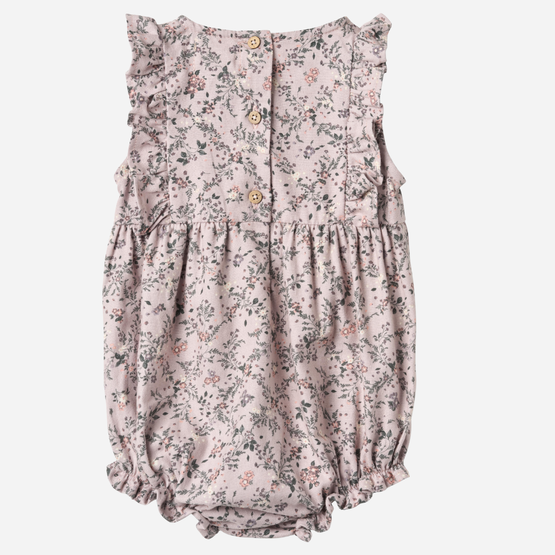 Sold at Bombon shop, designed by Wheat — sleeveless lilac floral baby romper with ruffled shoulders, gathered waist, and elasticized leg openings with snap closures for easy changing. back