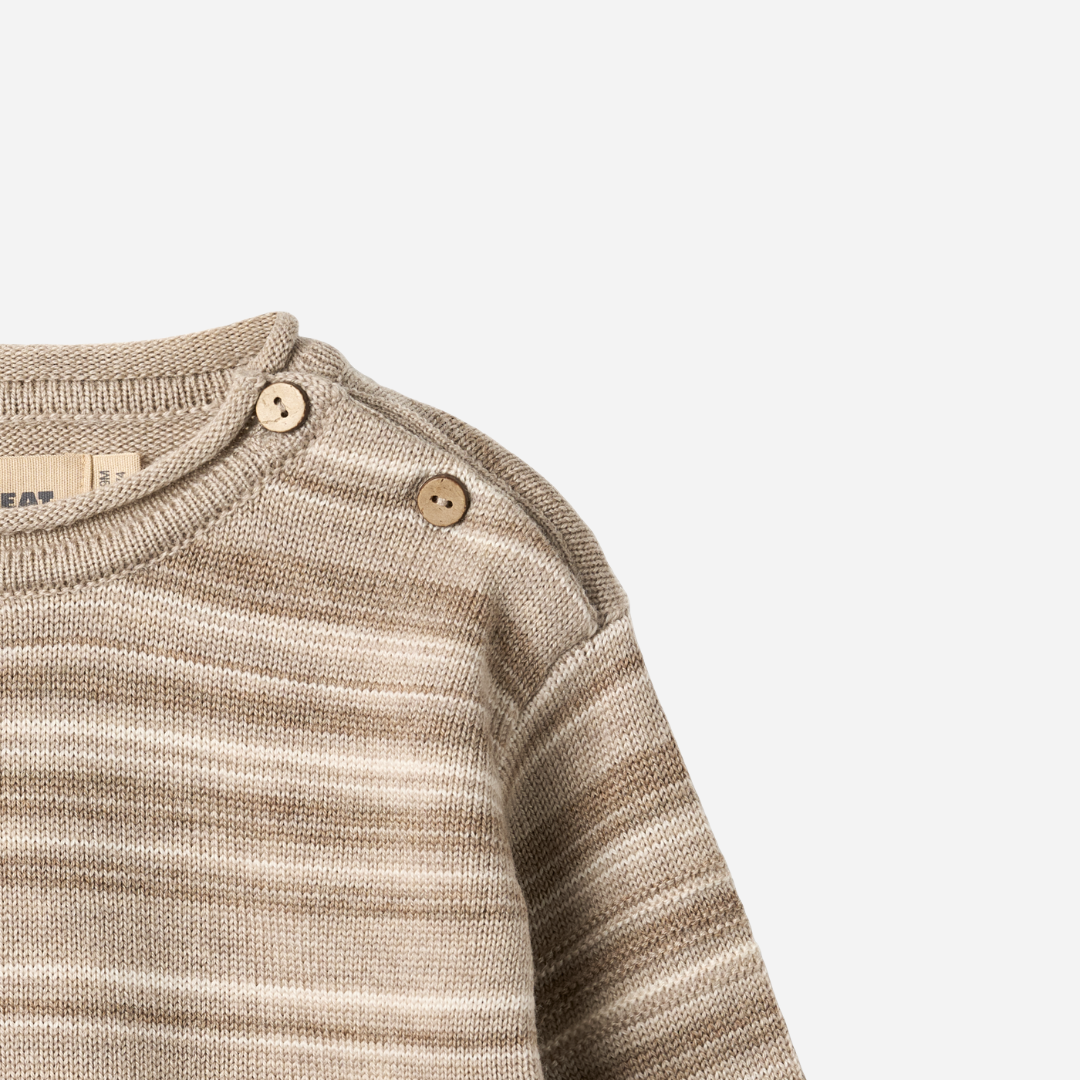 Sold at Bombon shop, designed by Wheat — knit baby sweater in warm sand stripe with shoulder buttons and soft texture. top