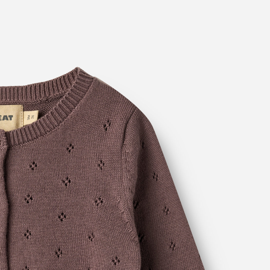 Sold at Bombon shop, designed by Wheat — plum-colored baby cardigan with delicate pointelle knit pattern, front button closure, and ribbed edges. top