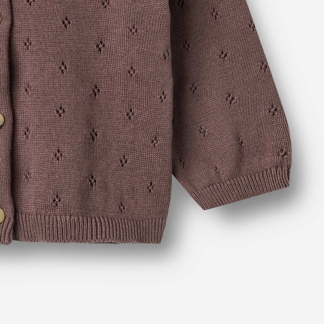 Sold at Bombon shop, designed by Wheat — plum-colored baby cardigan with delicate pointelle knit pattern, front button closure, and ribbed edges. bottom