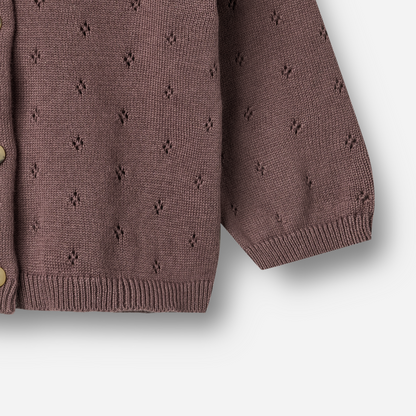 Sold at Bombon shop, designed by Wheat — plum-colored baby cardigan with delicate pointelle knit pattern, front button closure, and ribbed edges. bottom