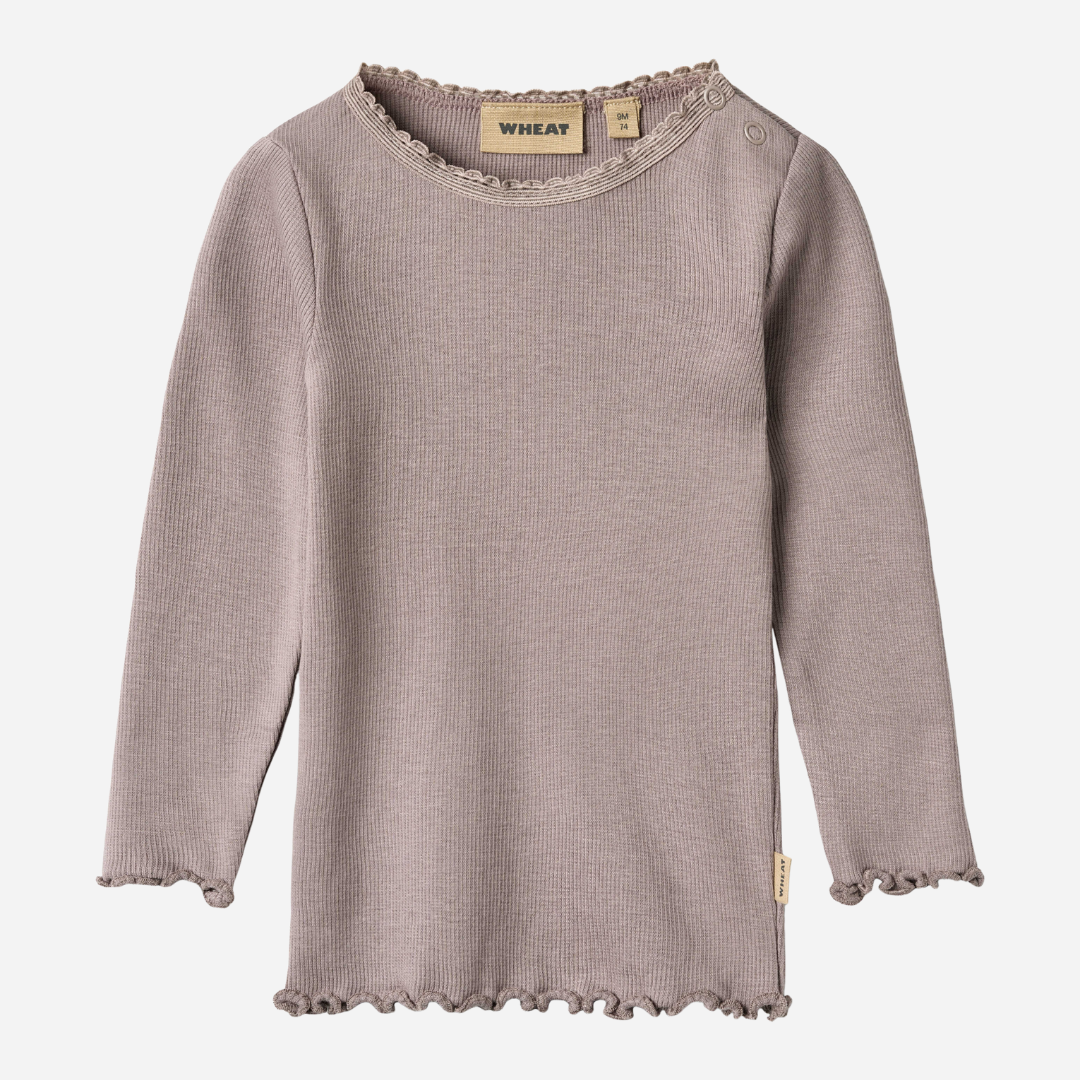 Sold at Bombon shop, designed by Wheat, this dusty purple ribbed long-sleeve tee features ruffle edges and a soft, stretchy finish. front