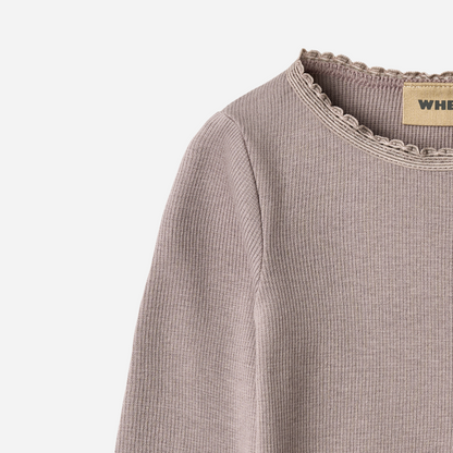 Sold at Bombon shop, designed by Wheat, this dusty purple ribbed long-sleeve tee features ruffle edges and a soft, stretchy finish. top