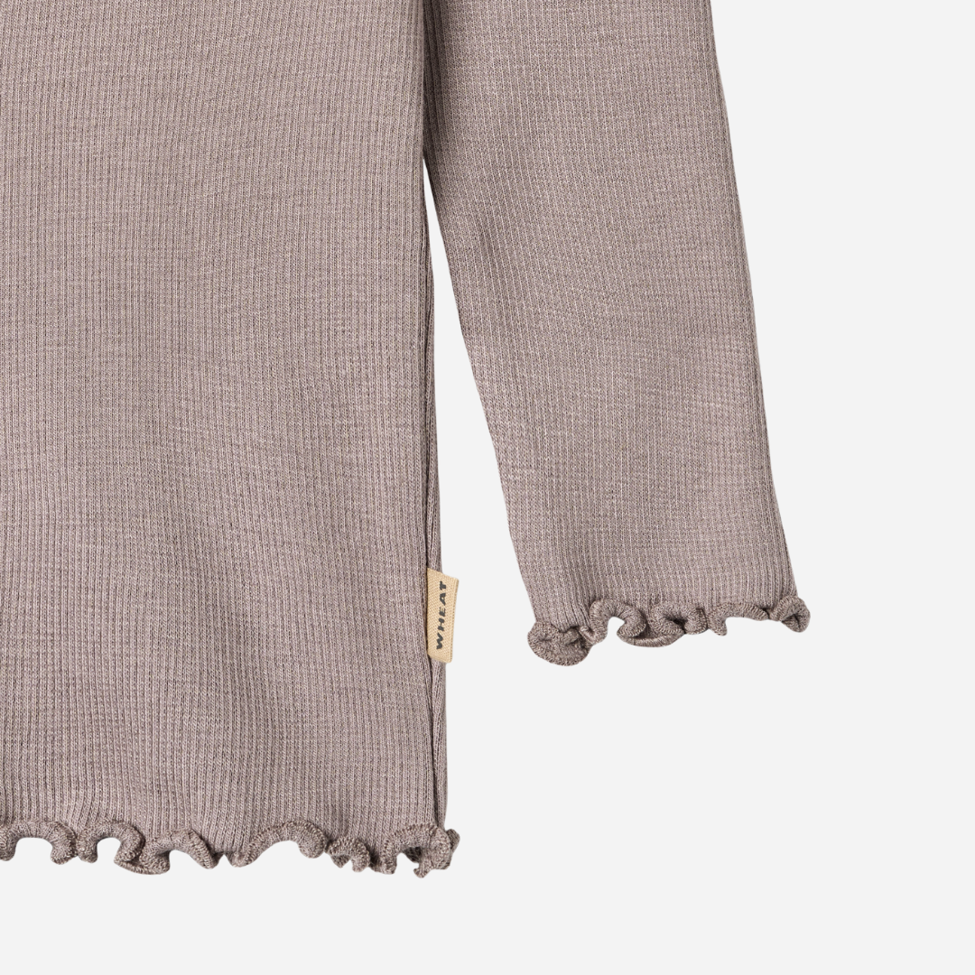 Sold at Bombon shop, designed by Wheat, this dusty purple ribbed long-sleeve tee features ruffle edges and a soft, stretchy finish. bottom