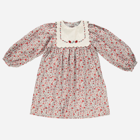 Sold at Bombon Shop, this Bebe Organic long-sleeve floral dress for baby and toddler girls features a vintage-inspired red and blue flower print, a scalloped ivory collar with delicate embroidery, and soft organic cotton fabric — a timeless piece for special occasions and everyday elegance.