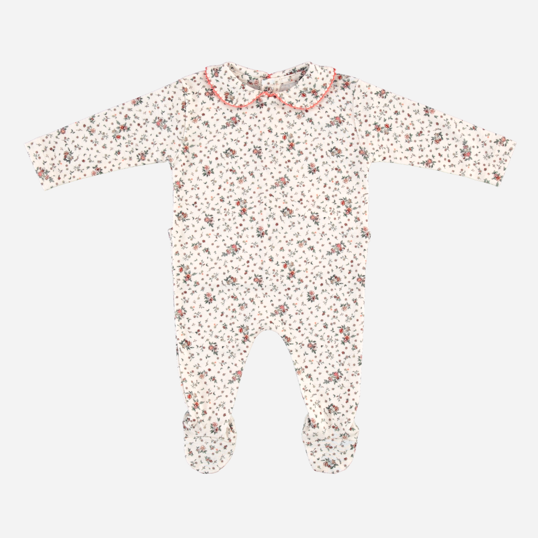 Sold at Bombon Shop, this Bebe Organic baby footed romper is made from soft organic cotton and features an allover vintage floral print, long sleeves, built-in feet, and a delicate Peter Pan collar with pink scalloped trim — a cozy and timeless essential for newborns and everyday comfort.