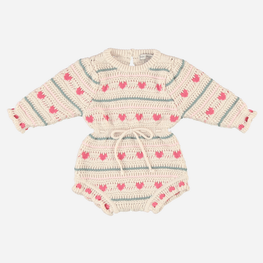Sold at Bombon Shop, this Bebe Organic baby girl knit romper is made from soft organic cotton with an adorable pink heart and stripe pattern, featuring long sleeves, a cinched waist with drawstring tie, and ruffled leg openings — a cozy and playful piece perfect for cooler days and special moments.