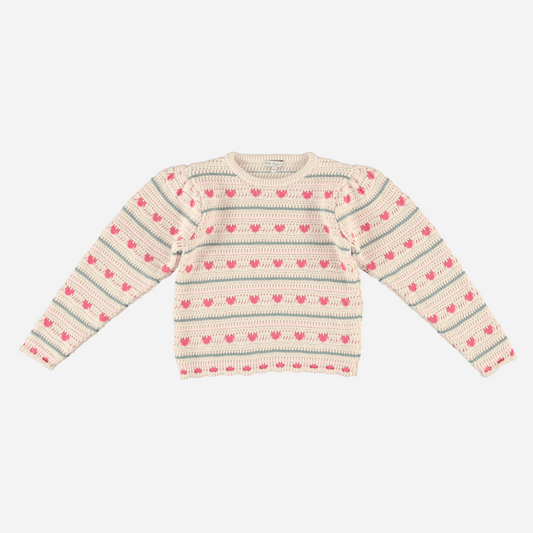Sold at Bombon Shop, this Bebe Organic girls’ knit sweater is made from soft organic cotton and features an allover pattern of pink hearts and soft blue stripes on a natural cream base — a cozy and playful cold-weather essential with a vintage feel, perfect for layering in fall and winter.