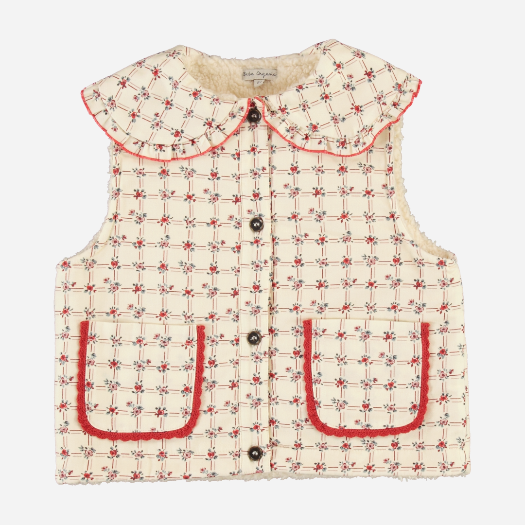 Sold at Bombon Shop, this Bebe Organic baby and toddler vest features a vintage-inspired checkered pattern in cream and red, crafted from soft wool with a cozy faux shearling lining, front button closure, scalloped Peter Pan collar, and patch pockets — a stylish and warm layering piece for fall and winter.