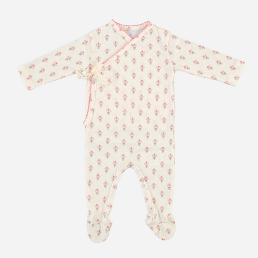 Sold at Bombon Shop, this Bebe Organic baby girl footed romper is made from soft organic cotton in a delicate floral print with pink trim, featuring a wrap-style front with bow tie closure for easy dressing — pair with the matching bonnet for a sweet and cozy newborn outfit perfect for everyday wear or gifting.