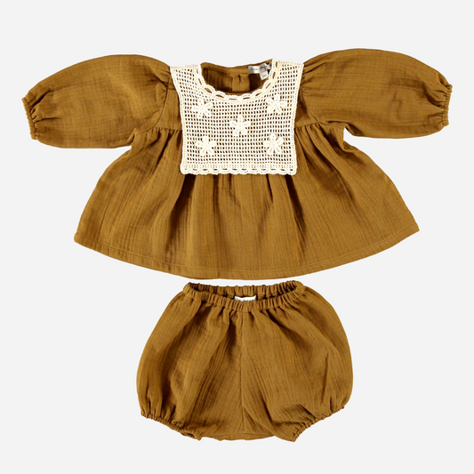 Sold at Bombon Shop, this Bebe Organic baby girl set features a rich caramel-toned organic cotton blouse with a hand-embroidered lace bib and gently puffed sleeves, paired with matching bloomers — a timeless and breathable outfit perfect for fall layering or transitional weather.
