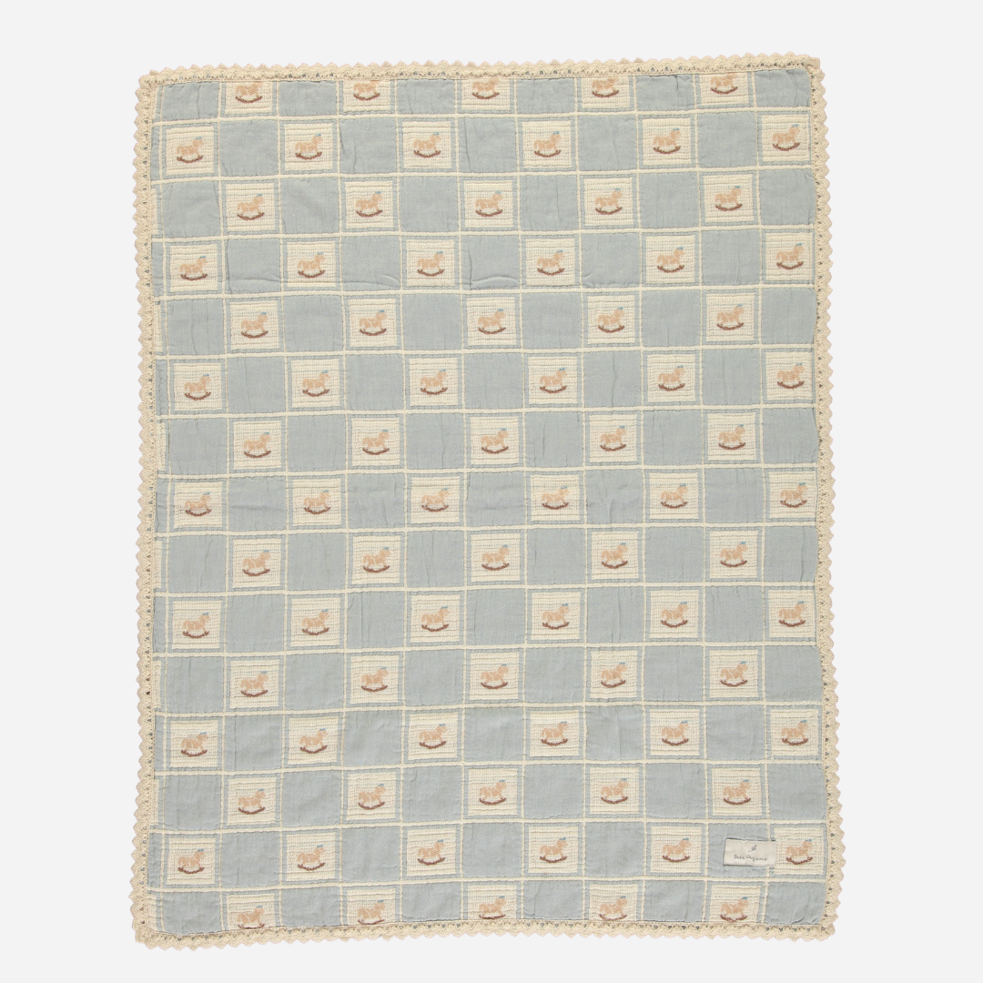 Sold at Bombon Shop, this Bebe Organic baby blanket is made from soft organic cotton muslin in a vintage-inspired duck print with a blue and cream checkered pattern, finished with delicate scalloped crochet trim — a cozy and charming essential for swaddling, stroller rides, or nursery decor.