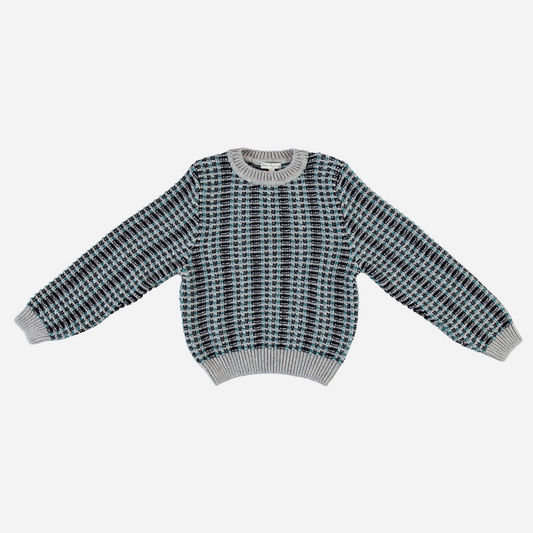 Sold at Bombon Shop, this Bebe Organic kids’ sweater is crafted from cozy organic wool in a stylish jacquard knit pattern featuring shades of grey, teal, and navy — a warm and timeless cold-weather essential perfect for baby and toddler boys