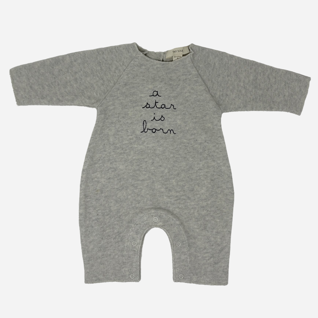 Sold at Bombon shop, designed by Tiny Soul — grey cotton baby romper with “a star is born” embroidery and bottom snap closures. front