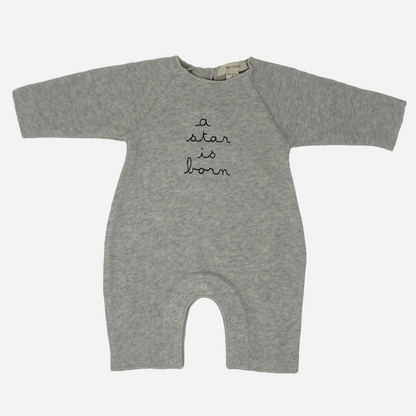 Sold at Bombon shop, designed by Tiny Soul — grey cotton baby romper with “a star is born” embroidery and bottom snap closures. front