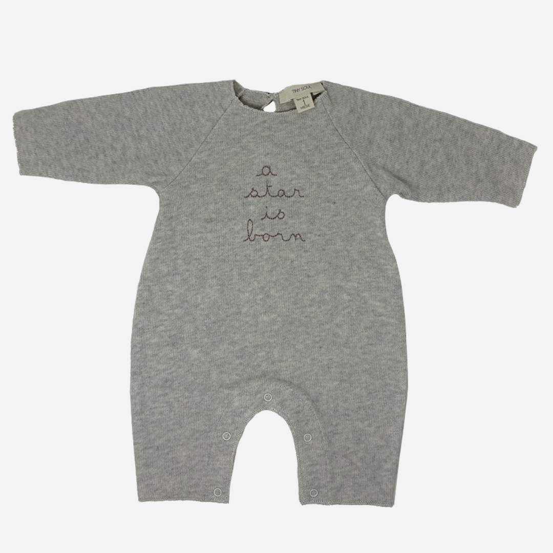 Sold at Bombon shop, designed by Tiny Soul — grey cotton baby romper with “a star is born” embroidery and bottom snap closures. front