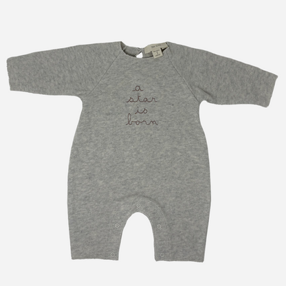 Sold at Bombon shop, designed by Tiny Soul — grey cotton baby romper with “a star is born” embroidery and bottom snap closures. front