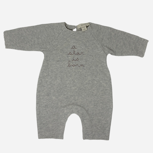 Sold at Bombon shop, designed by Tiny Soul — grey cotton baby romper with “a star is born” embroidery and bottom snap closures. front